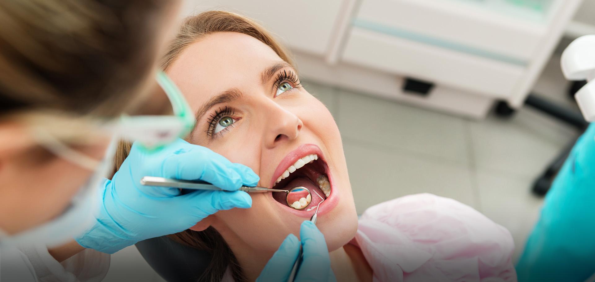 Slajd #3 - stomatolog przeglądający stan uzębienia klientki